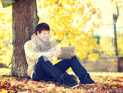 Image of man with tablet pc in autumn park