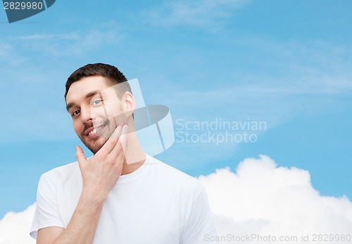 Image of beautiful smiling man touching his face