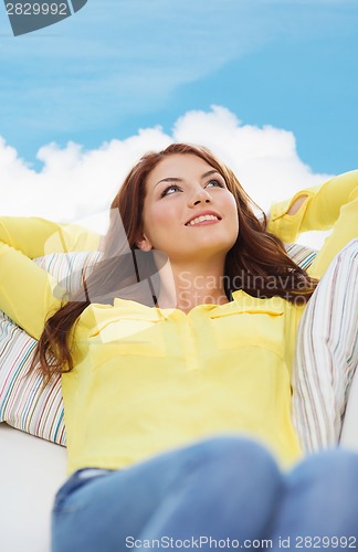 Image of smiling young woman lying on sofa at home