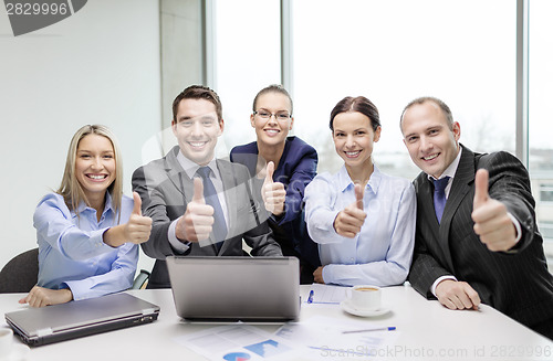 Image of business team showing thumbs up in office