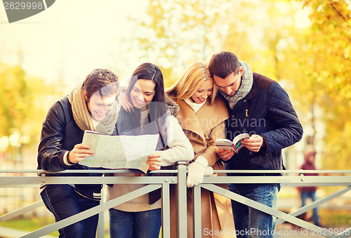 Image of couples with tourist map in autumn park