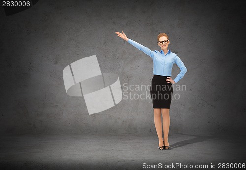 Image of smiling businesswoman in glasses pointing her hand