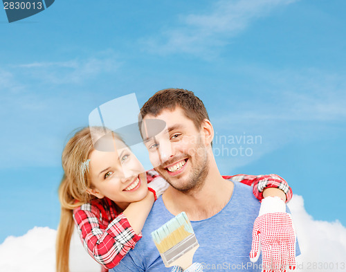 Image of smiling couple covered with paint with paint brush