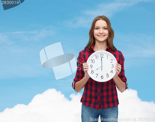 Image of young woman in casual clothes with wall clock