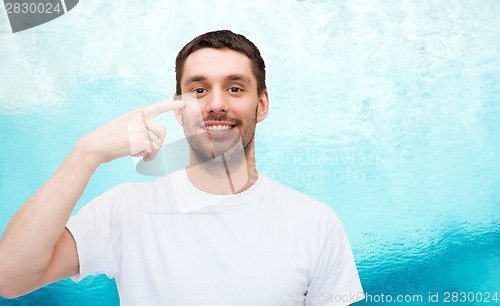 Image of smiling young handsome man pointing to eyes