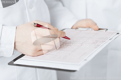 Image of male doctor hands holding cardiogram