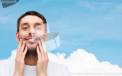 Image of beautiful smiling man touching his face