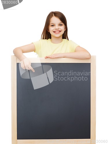 Image of happy little girl pointing finger to blackboard