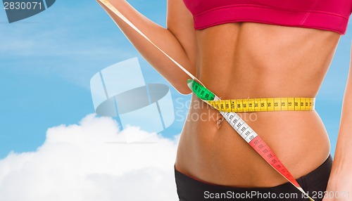 Image of close up of trained belly with measuring tape