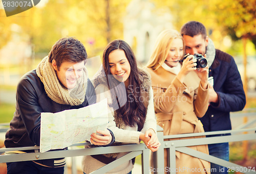 Image of couples with tourist map and camera in autumn park