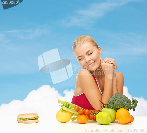 Image of doubting woman with fruits and hamburger