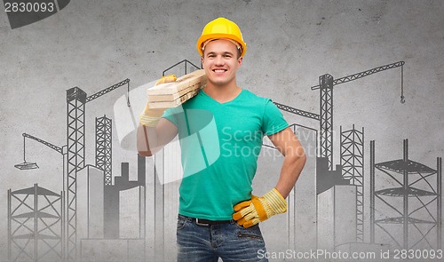 Image of smiling manual worker in helmet with wooden boards