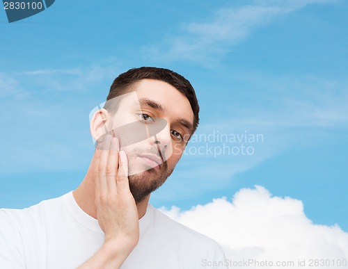 Image of beautiful calm man touching his face