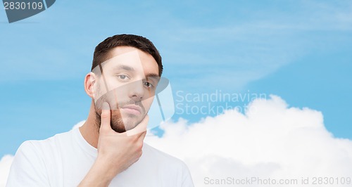 Image of beautiful calm man touching his face