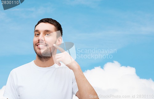 Image of smiling young handsome man pointing to cheek