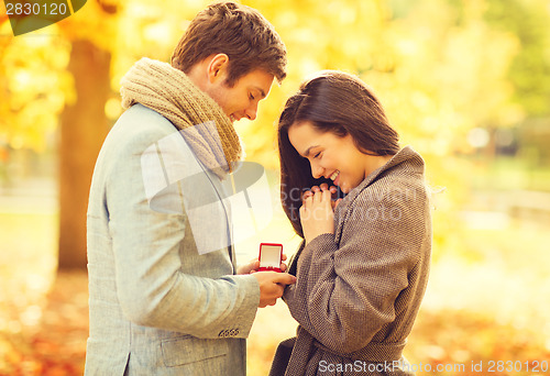 Image of man proposing to a woman in the autumn park