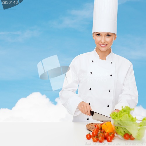 Image of smiling female chef chopping vegetables