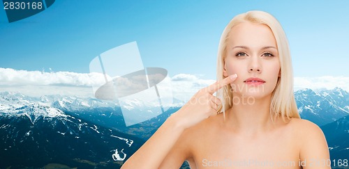 Image of calm young woman pointing at her cheek