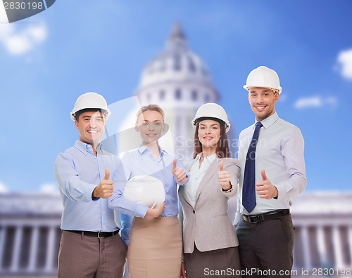 Image of happy business team in office showing thumbs up