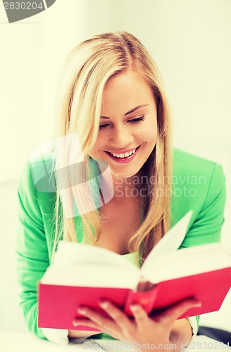 Image of smiling young woman reading book at school
