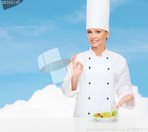 Image of smiling female chef with salad on plate