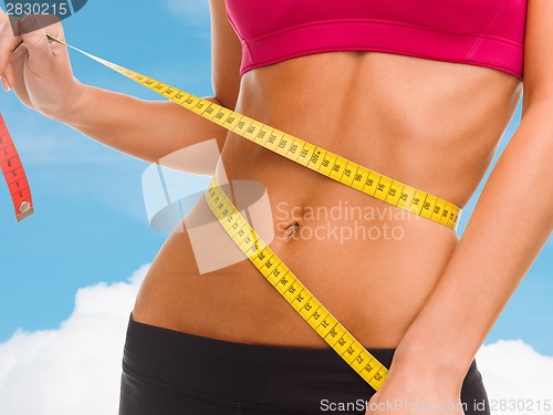 Image of close up of trained belly with measuring tape