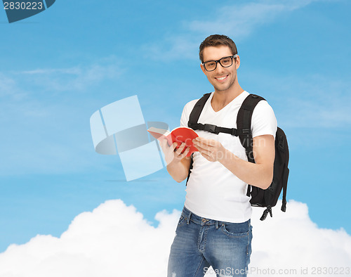 Image of travelling student with backpack and book