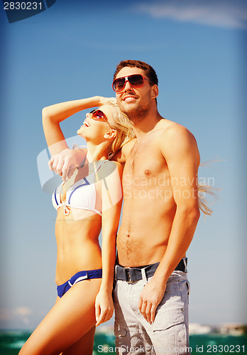 Image of happy couple in sunglasses on the beach