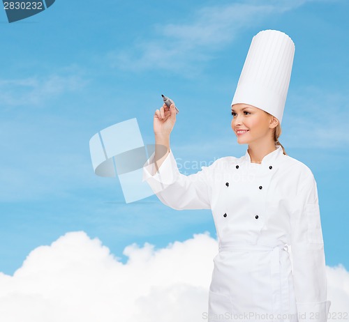 Image of smiling female chef writing something on air