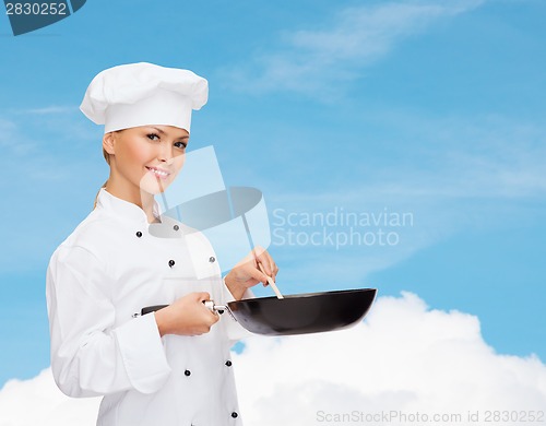 Image of smiling female chef with pan and spoon