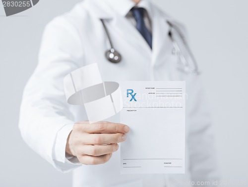 Image of male doctor holding rx paper in hand