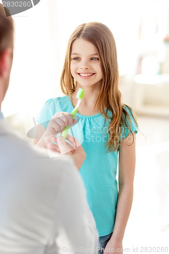 Image of male doctor giving toothbrush to smiling girl