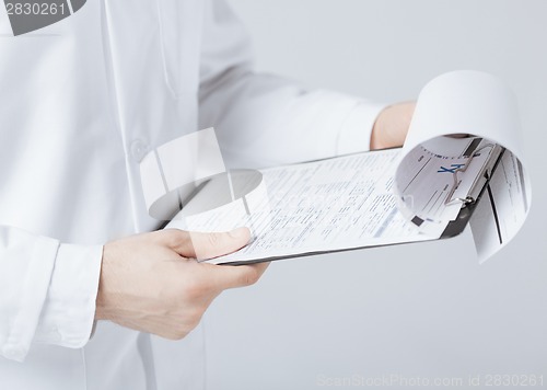 Image of male doctor holding prescription paper in hand