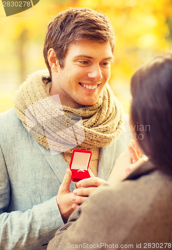 Image of man proposing to a woman in the autumn park
