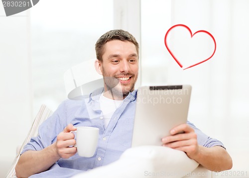 Image of smiling man working with tablet pc at home