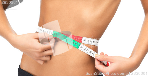 Image of woman measuring her waist with measuring tape