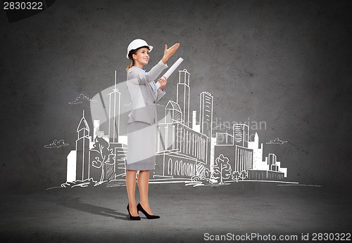 Image of smiling architect in helmet with blueprint