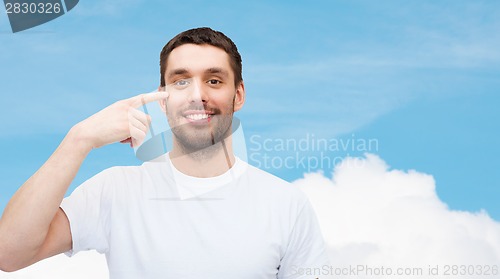 Image of smiling young handsome man pointing to eyes