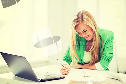 Image of smiling student girl writing in notebook