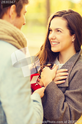 Image of man proposing to a woman in the autumn park