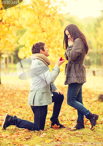 Image of man proposing to a woman in the autumn park