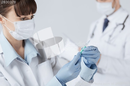 Image of female doctor holding syringe with injection