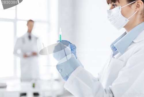 Image of female doctor holding syringe with injection