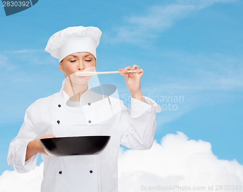 Image of smiling female chef with pan and spoon