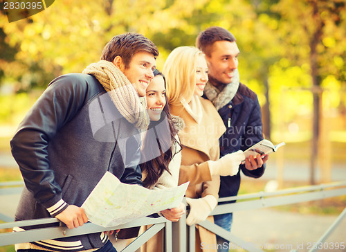 Image of couples with tourist map in autumn park