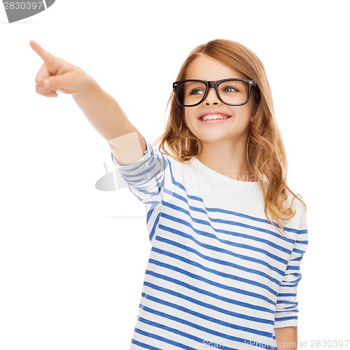 Image of cute little girl in eyeglasses pointing in the air