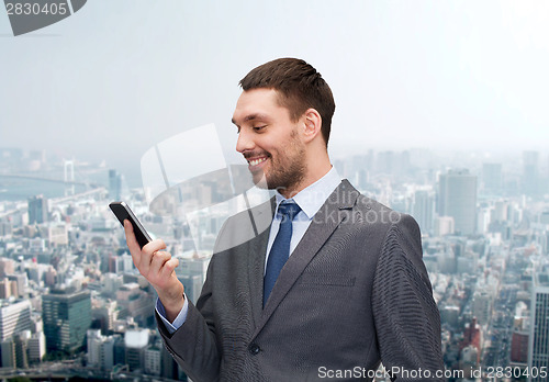 Image of young smiling businessman with smartphone