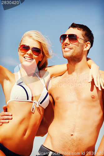 Image of happy couple in sunglasses on the beach