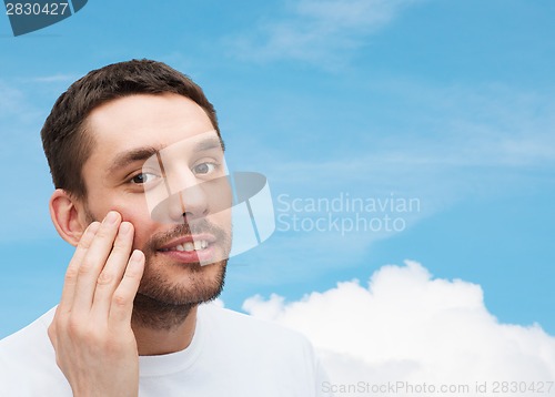 Image of beautiful smiling man touching his face