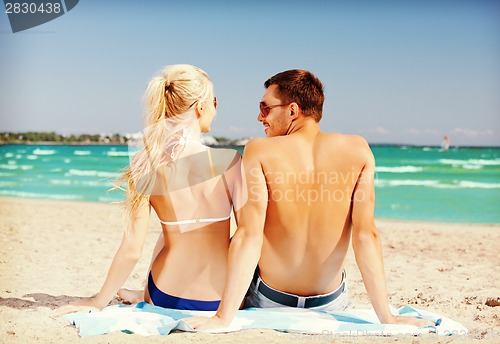 Image of happy couple sitting on the beach